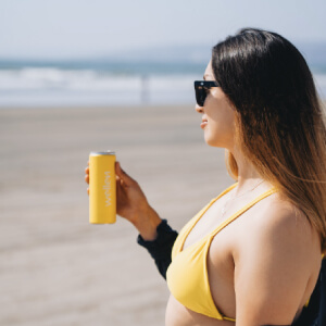 Mujer sosteniendo lata wellen en la playa